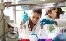 Two young female students using a pipette and samples in a lab.