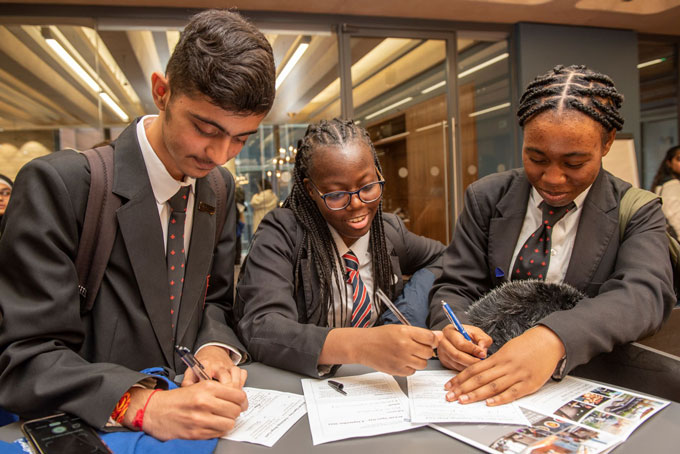 Three students writing on worksheets.